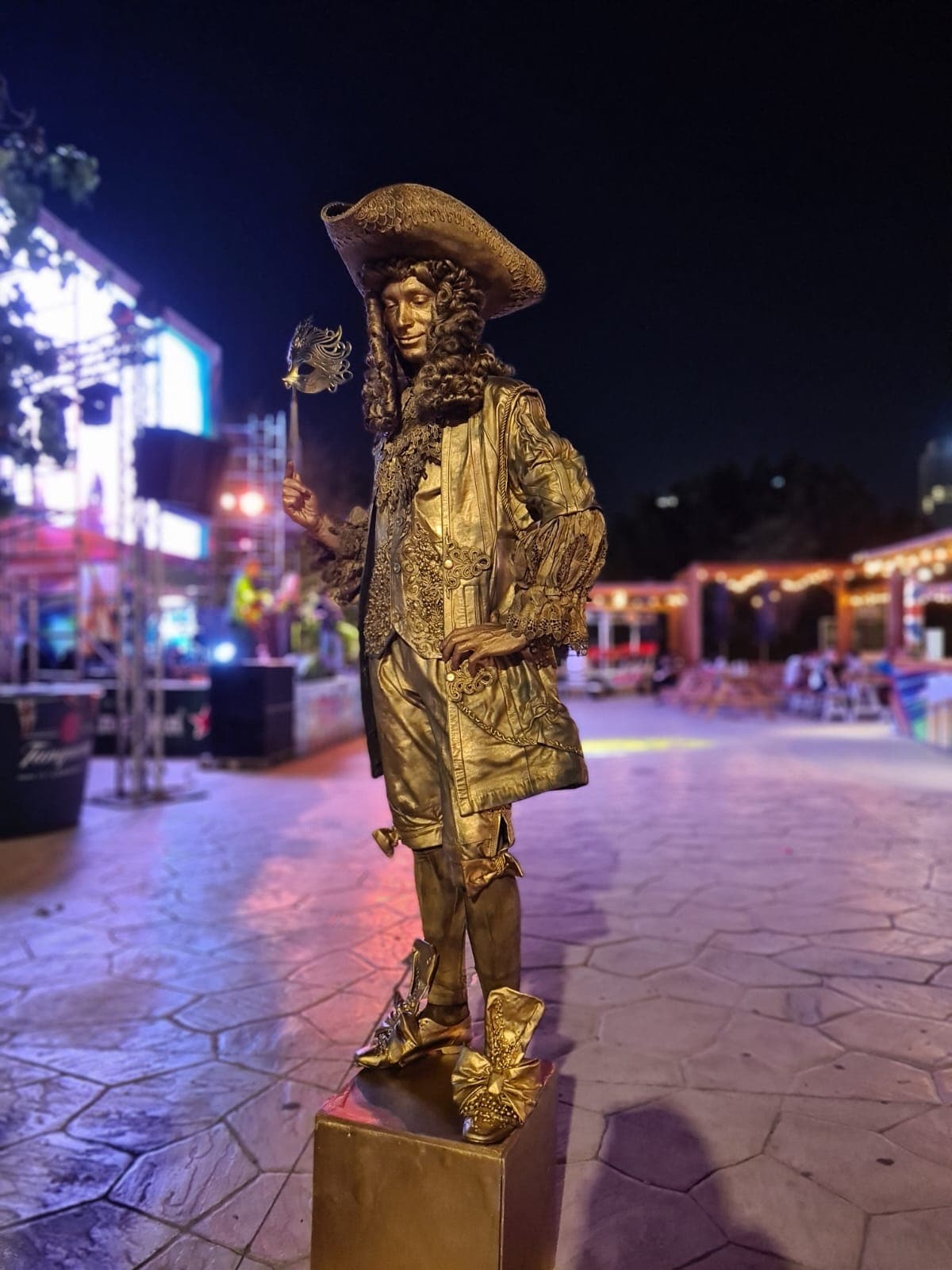 Gold-painted living statue performer posing at an evening event