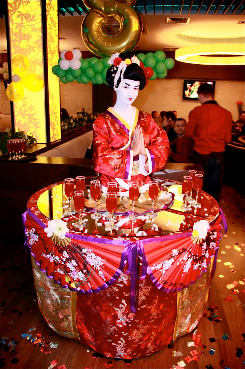 Living table performer in geisha costume serving drinks at an event