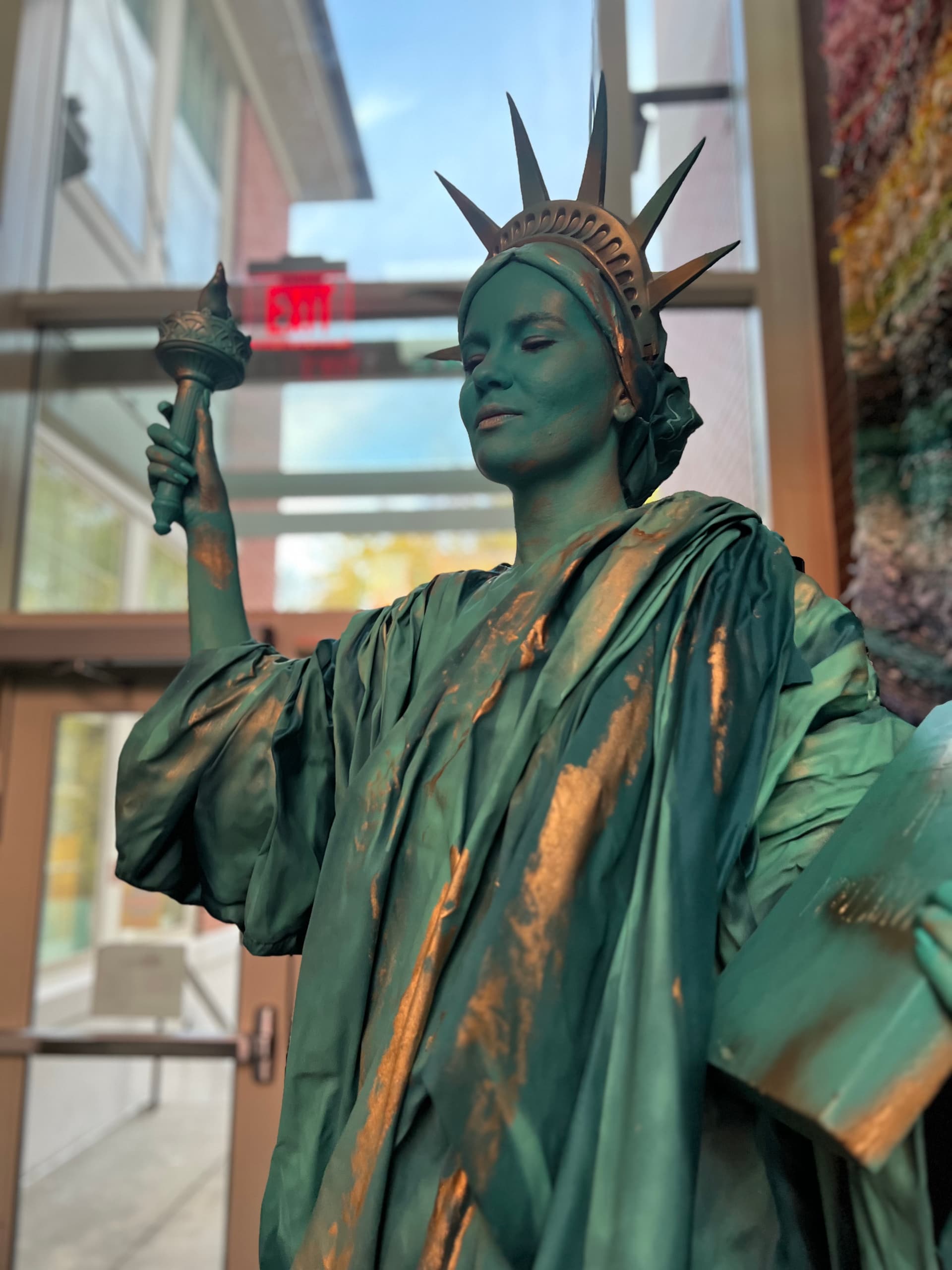 Living statue performer painted as the Statue of Liberty with torch and tablet